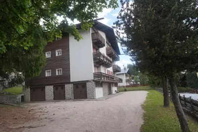 a large building with wooden doors and a dirt road at FALORIA Studio Apartment in Cortina dʼAmpezzo