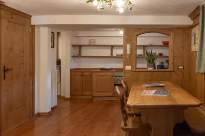 a kitchen with a wooden table and a dining room at FALORIA Studio Apartment in Cortina dʼAmpezzo