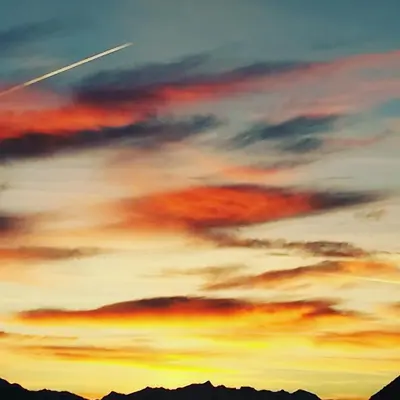 a plane is flying in the sky at sunset at Pension Apartments Klotznerhof in Schenna