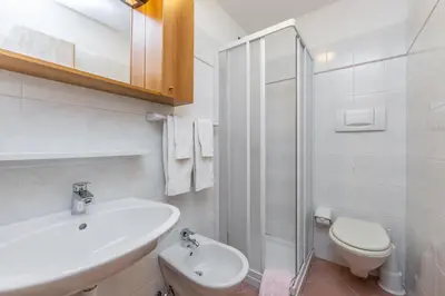 a white bathroom with a sink and a toilet at Rifugio Cereda in Fiera di Primiero