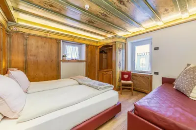 a room with two beds and a chair at Rifugio Cereda in Fiera di Primiero