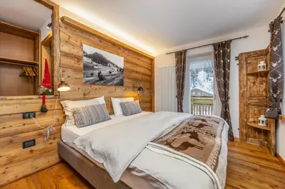 a bedroom with a large bed with a wooden wall at Rifugio Cereda in Fiera di Primiero