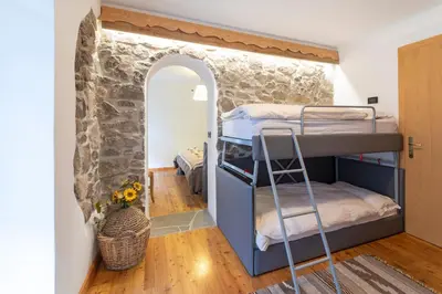 a bedroom with bunk beds and a stone wall at Rifugio Cereda in Fiera di Primiero