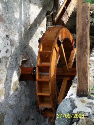 a wooden spiral staircase next to a stone wall at Apartment Furschermuehle in Siusi