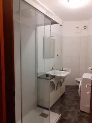 a bathroom with a glass shower with a sink at Appartamento ospitale in Bolzano