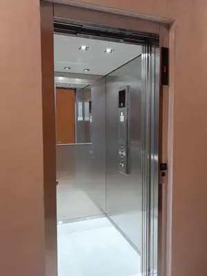 a glass elevator in a building with a mirror at Appartamento ospitale in Bolzano