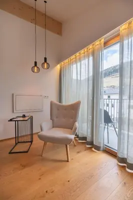a chair in a living room with a large window at Steindls Boutique Favourite in Vipiteno