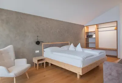 a bedroom with a large bed and a chair at Steindls Boutique Favourite in Vipiteno