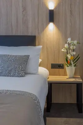 a bedroom with a bed and a table with a vase of flowers at Tourist Hotel in Bressanone
