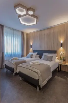 a bedroom with two beds and a chandelier at Tourist Hotel in Bressanone