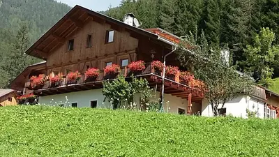 a house on a hill with red flowers on its balcony at Pastrogn 4 in La Valle