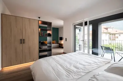 a bedroom with a large white bed and a sliding glass door at Sambucus Apartments -Premium Apartments for You and Your Dog in Lana