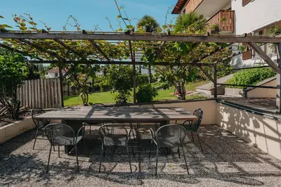 a table and chairs sitting under a wooden pergola at Hotel Römerrast in Caldaro