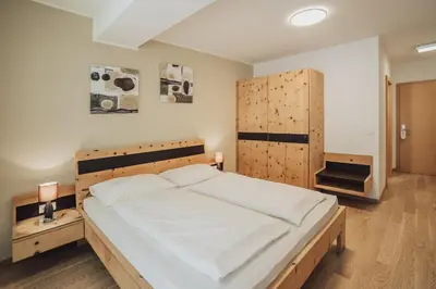 a bedroom with a large bed with a wooden headboard at Hotel Römerrast in Caldaro
