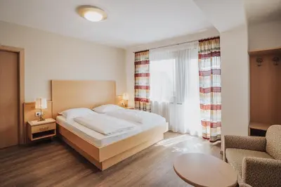 a hotel room with a bed and a chair at Hotel Römerrast in Caldaro