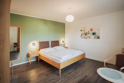 a bedroom with a large white bed and a mirror at Hotel Römerrast in Caldaro