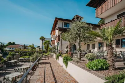 a walkway in front of a building with tables and chairs at Hotel Römerrast in Caldaro