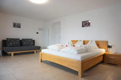 a bedroom with a bed with white pillows and a couch at Zum Schwarzen Kus in Caldaro