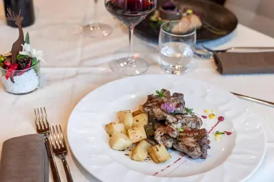 a plate of food on a table with wine glasses at Hotel Cant del Gal in Fiera di Primiero