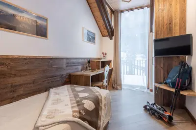 a bedroom with a bed and a desk and a television at Hotel Cant del Gal in Fiera di Primiero