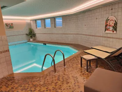 a swimming pool with a table and a bench in front of it at Hotel Alpenblick in Sarntal