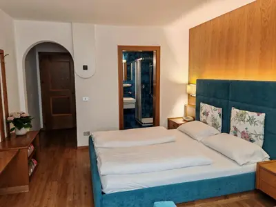 a bedroom with a large bed with a blue headboard at Hotel Alpenblick in Sarntal