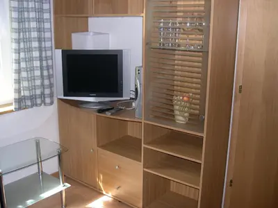 a television sitting on a wooden cabinet with a shelf at Obergereuth Hof 1288 in San Martino
