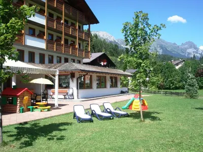 a group of chairs in the grass in front of a building at Sport Hotel Cristal in Falcade