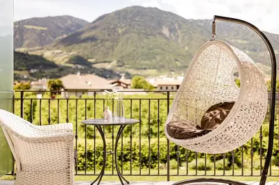 a hammock chair and a table on a balcony with mountains at Garden Residence in Lana