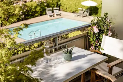 a table with wine glasses on a balcony with a swimming pool at Garden Residence in Lana