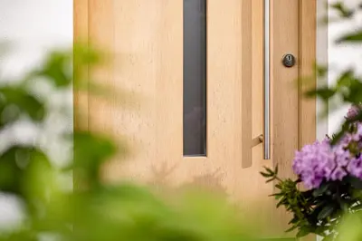 a wooden door with a window and purple flowers at Garden Residence in Lana
