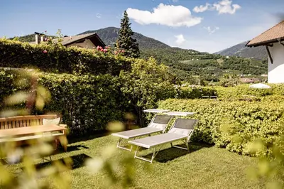 a garden with two chairs and a bench at Garden Residence in Lana