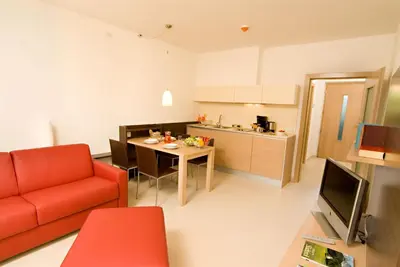 a living room with a red couch and a kitchen at Garden Residence in Lana