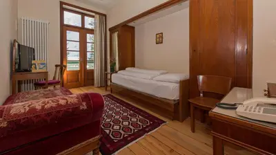 a bedroom with a bed and a desk with a computer at Hotel Lago di Braies in Braies
