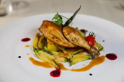 a white plate with a dish with chicken and vegetables at Hotel Lago di Braies in Braies