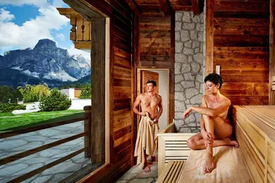 a man and a woman sitting in a sauna at Hotel Costes in Corvara in Badia