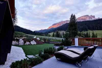 a chair on a patio with a view of a mountain at Hotel Costes in Corvara in Badia