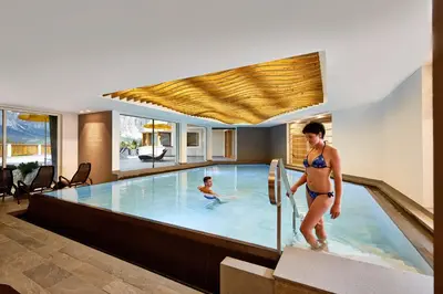 a woman in a swimming pool with a boy at Hotel Costes in Corvara in Badia