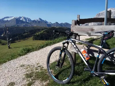 a bike parked next to a bench with mountains in the background at Hotel Costes in Corvara in Badia