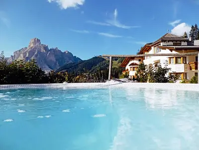 a swimming pool with a mountain in the background at Hotel Costes in Corvara in Badia