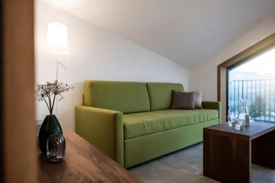 a living room with a green couch and a table at Papstlhof in Caldaro