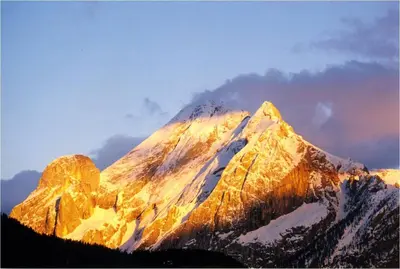 a snow covered mountain with the sun shining on it at Chalet Tobià Apartments in Canazei