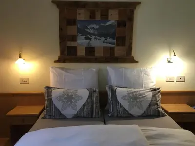 a bedroom with a bed with white sheets and pillows at Chalet Tobià Apartments in Canazei