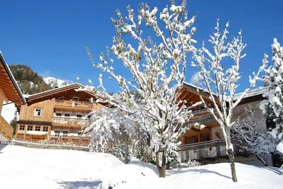 a ski lodge in the snow with two trees at Chalet Tobià Apartments in Canazei