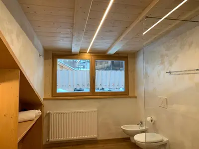 a bathroom with a toilet and a sink and a window at Chalet Tobià Apartments in Canazei