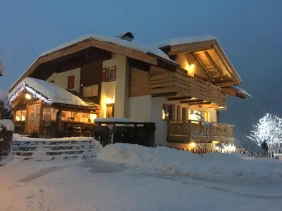 a house covered in snow at night at Chalet Tobià Apartments in Canazei