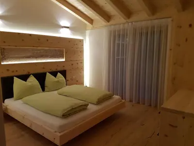 a bedroom with a large bed with a wooden headboard at El Paradiso in Naturno