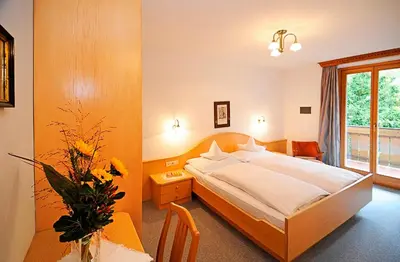 a bedroom with a bed and a table and a window at Pension Laurin in Schenna