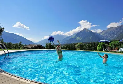 two girls playing with a ball in a swimming pool at Pension Laurin in Schenna