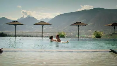 a man and a woman sitting in a swimming pool at Boutique Hotel Eschenlohe Adults only in Schenna